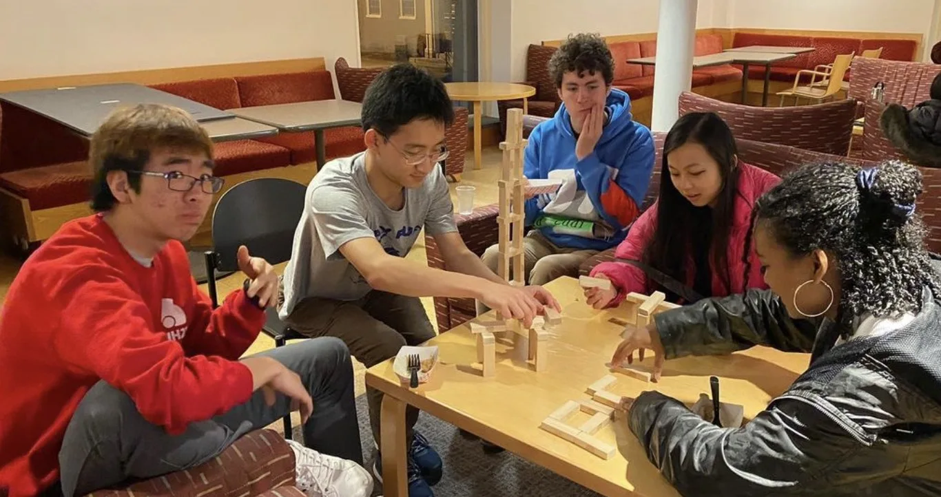 Students building with wooden blocks around a table